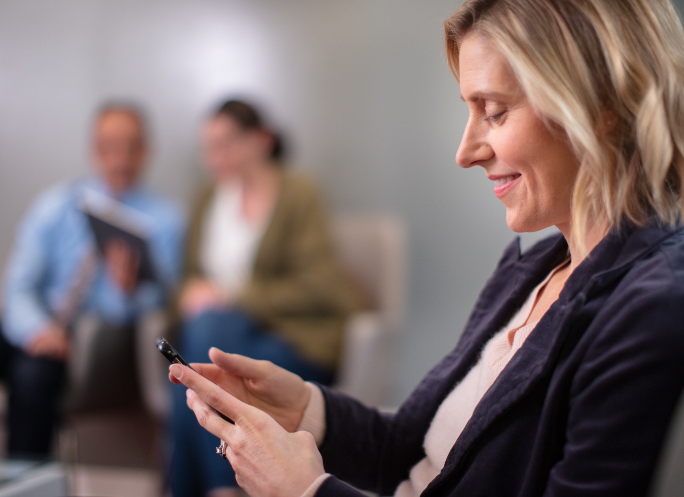 A businesswoman smiling and using CCaaS tools on her smartphone.