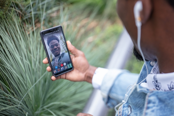 Man outdoors using 8x8 video conferencing solutions on his smartphone to collaborate with teammate